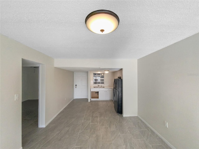 tiled empty room featuring a textured ceiling