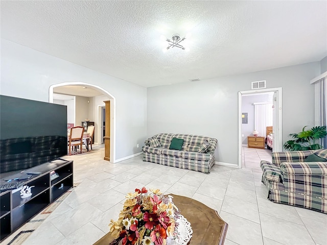 living room with a textured ceiling and light tile floors