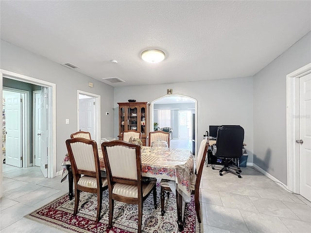 tiled dining space with a textured ceiling