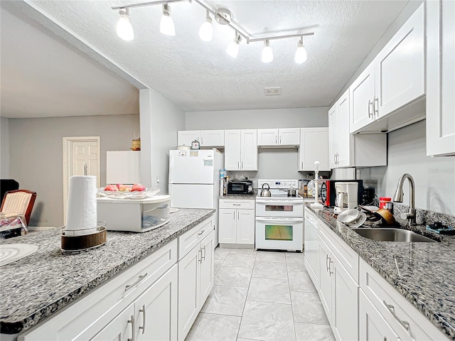 kitchen featuring white appliances, white cabinetry, light stone counters, and sink