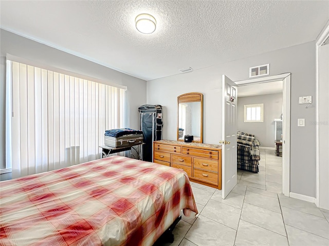 bedroom with a textured ceiling and light tile flooring