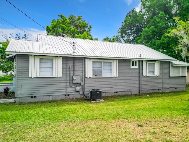 back of house featuring central AC unit and a lawn