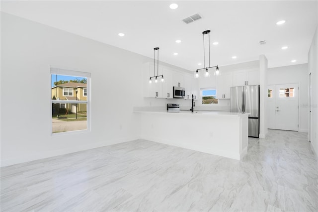 kitchen with pendant lighting, light tile floors, appliances with stainless steel finishes, a wealth of natural light, and white cabinetry