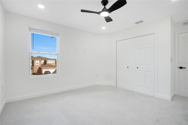 unfurnished bedroom with light colored carpet, a closet, and ceiling fan