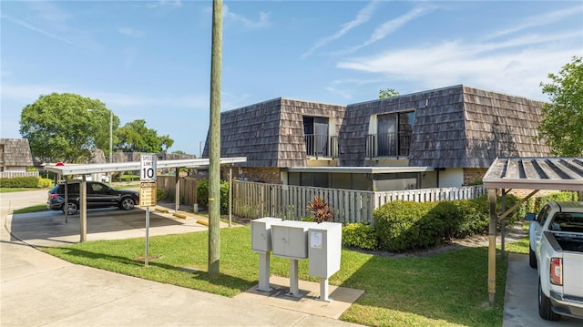 exterior space with a balcony, a carport, and a front lawn