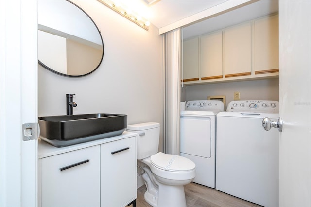 interior space with vanity, toilet, independent washer and dryer, and hardwood / wood-style floors