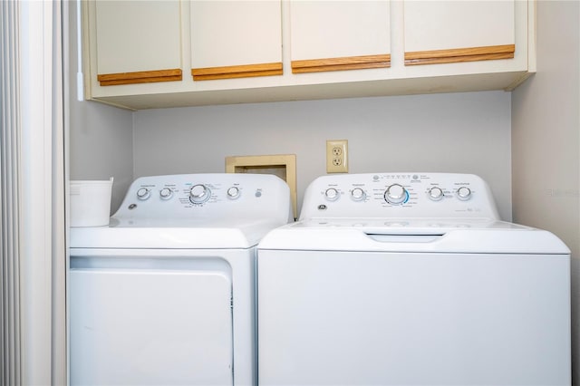 clothes washing area featuring cabinets and washing machine and dryer