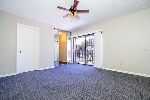 empty room with ceiling fan, dark colored carpet, and a textured ceiling