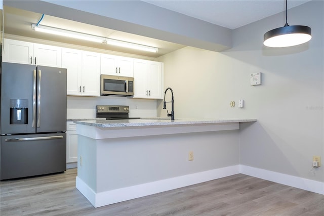 kitchen featuring hanging light fixtures, stainless steel appliances, light wood-type flooring, and white cabinets