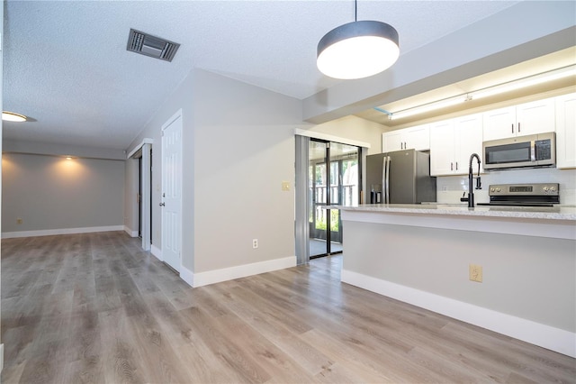 kitchen featuring light hardwood / wood-style flooring, appliances with stainless steel finishes, and white cabinetry