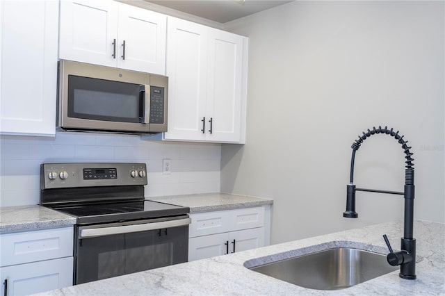 kitchen featuring light stone countertops, sink, stainless steel appliances, and white cabinets