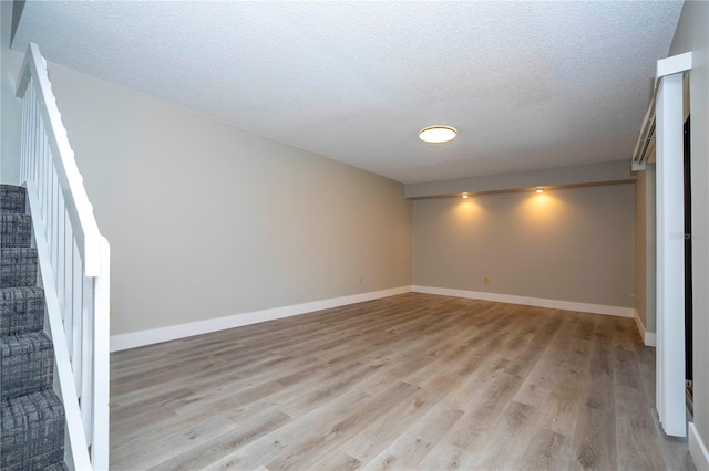 empty room with a textured ceiling and light hardwood / wood-style flooring