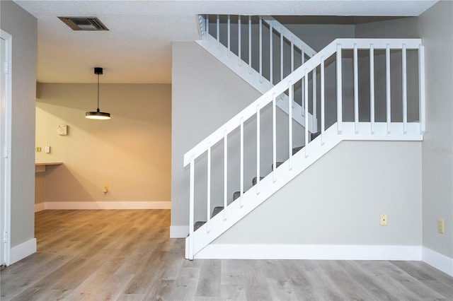 stairway featuring a textured ceiling and hardwood / wood-style floors