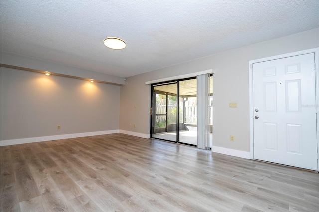 spare room featuring a textured ceiling and light hardwood / wood-style floors