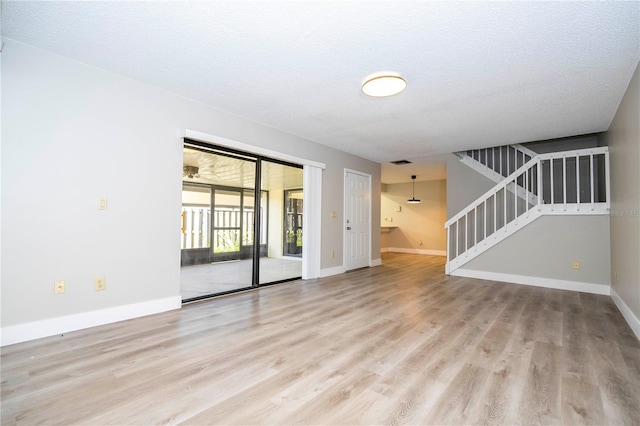 spare room featuring light wood-type flooring and a textured ceiling