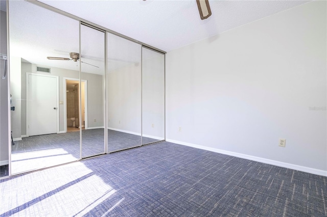 unfurnished bedroom featuring a textured ceiling, carpet, a closet, and ceiling fan