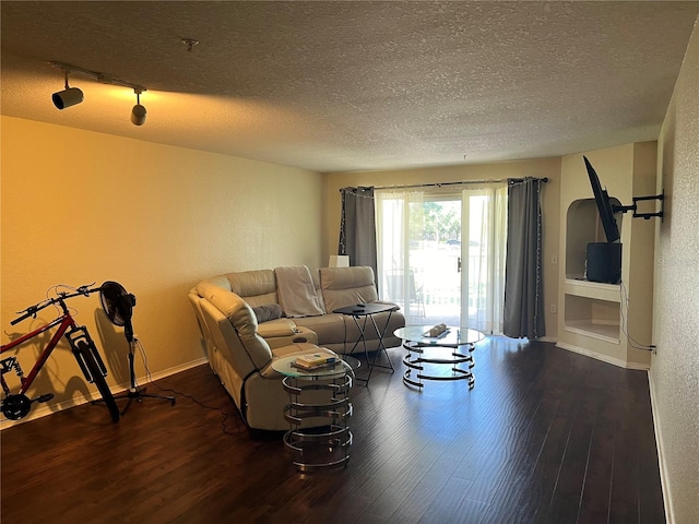 living room featuring rail lighting, a textured ceiling, and dark wood-type flooring