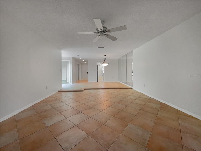 tiled empty room with a textured ceiling and ceiling fan