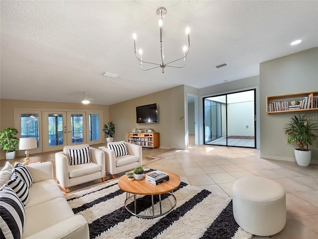 tiled living room featuring ceiling fan with notable chandelier, french doors, and a textured ceiling