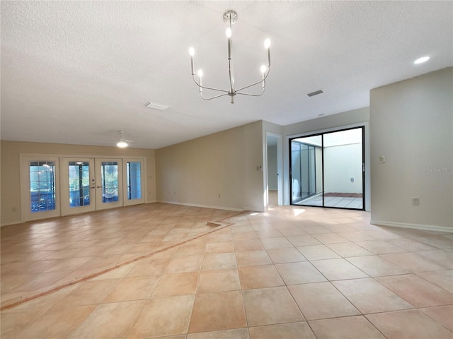 tiled empty room featuring a textured ceiling, french doors, and ceiling fan with notable chandelier