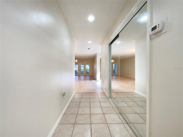 corridor featuring a textured ceiling, french doors, and light tile patterned floors