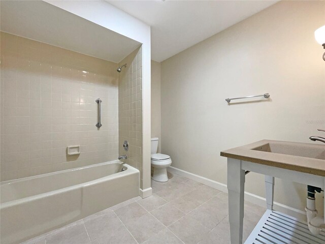 bathroom featuring tile patterned floors, toilet, and tiled shower / bath combo