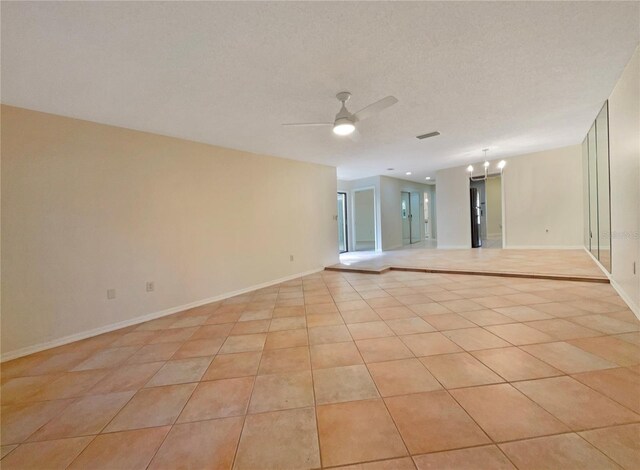 tiled empty room featuring ceiling fan and a textured ceiling