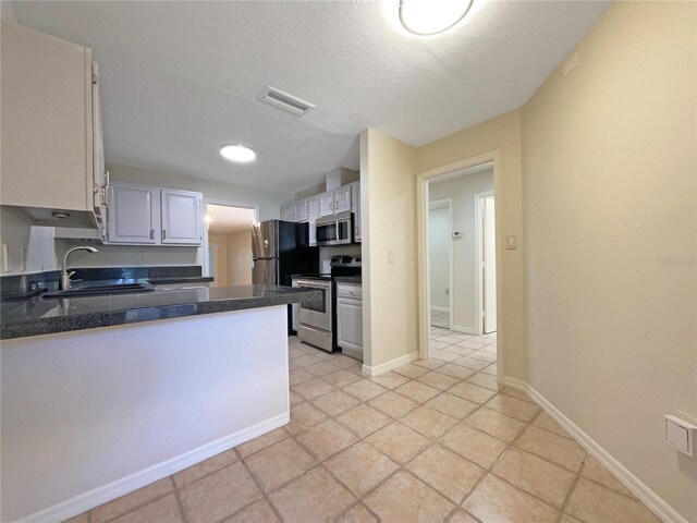 kitchen with kitchen peninsula, stainless steel appliances, sink, a textured ceiling, and white cabinets