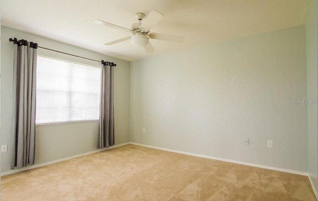 spare room featuring light carpet, ceiling fan, and baseboards