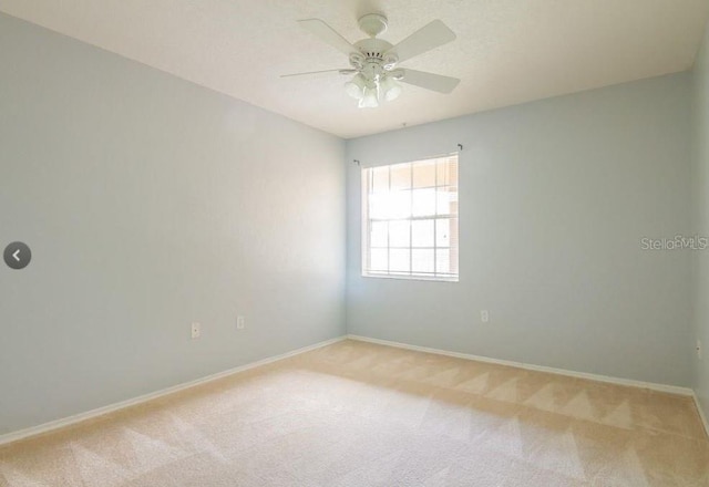 unfurnished room with a ceiling fan, light colored carpet, and baseboards