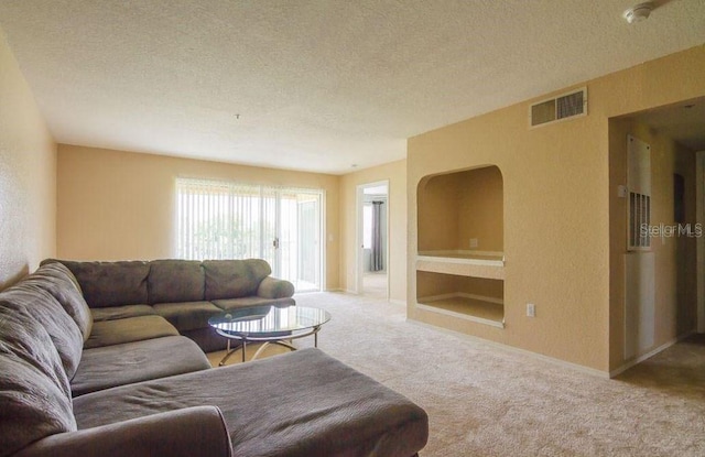 carpeted living area featuring visible vents and a textured ceiling