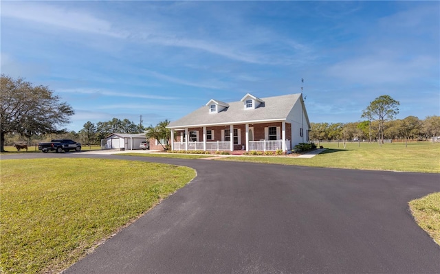 cape cod house featuring covered porch, a storage unit, and a front lawn