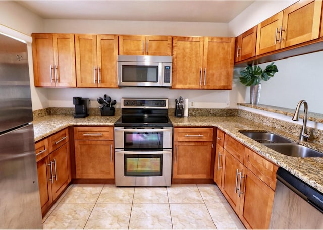 kitchen featuring light tile patterned floors, stainless steel appliances, light stone counters, and sink