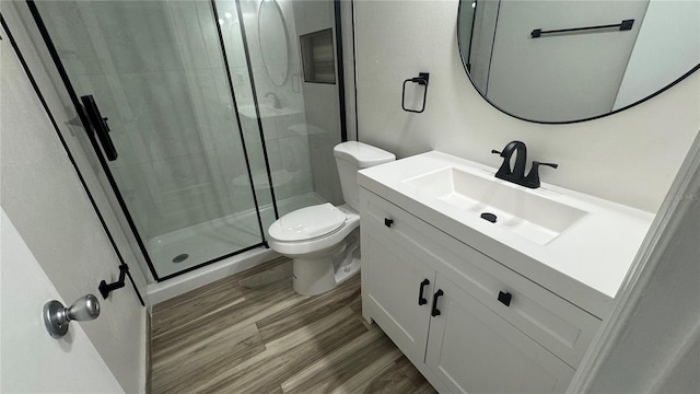 bathroom with toilet, hardwood / wood-style flooring, vanity, and a shower with door