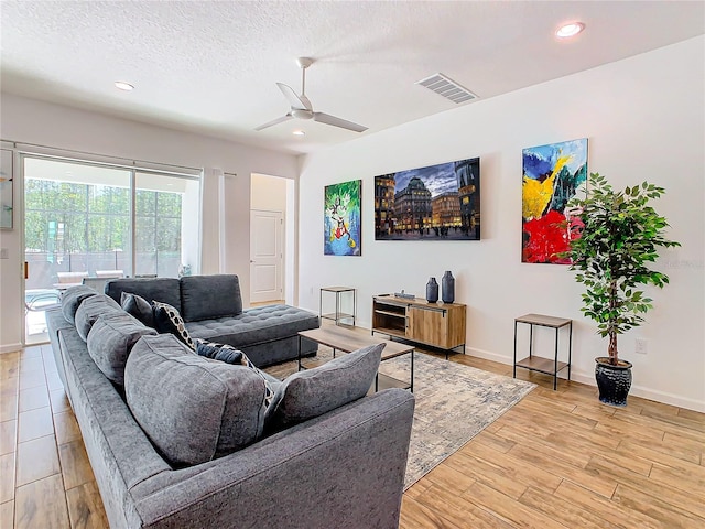 living room featuring a textured ceiling, ceiling fan, and light hardwood / wood-style flooring