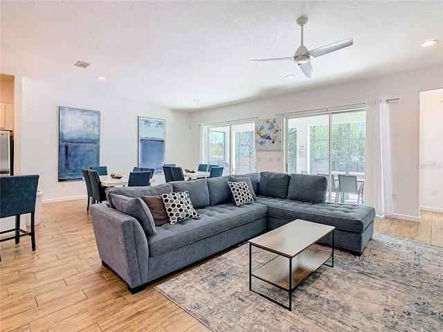 living room with light wood-type flooring, ceiling fan, a textured ceiling, and french doors