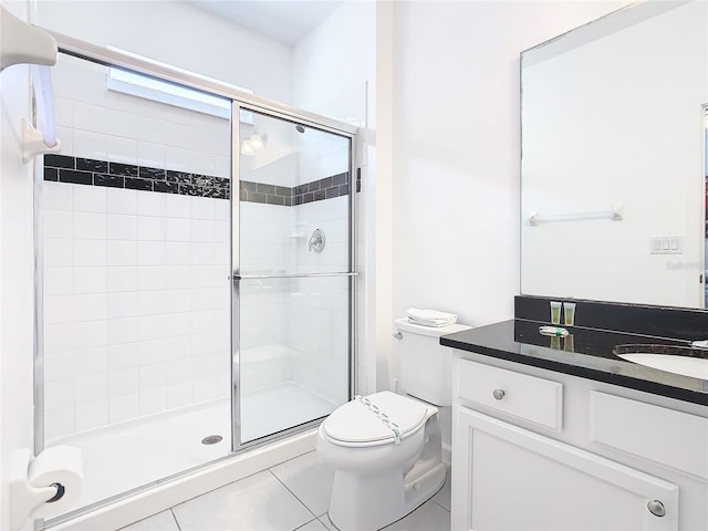 bathroom featuring tile floors, toilet, vanity, and a shower with door