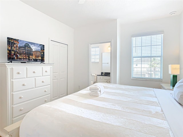 bedroom with a closet, multiple windows, and ensuite bath