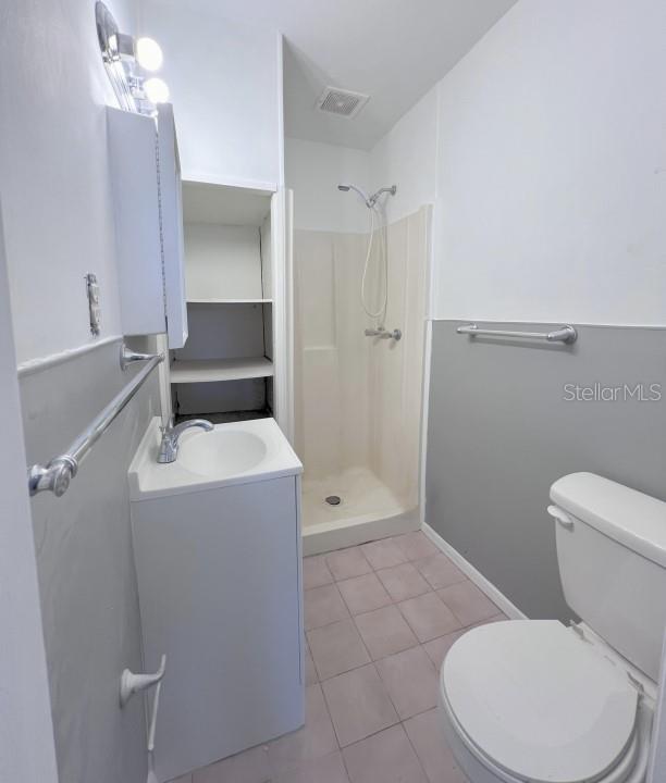 bathroom with vanity, toilet, tile patterned floors, and a shower