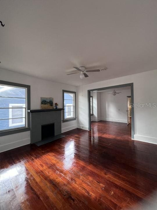 unfurnished living room featuring ceiling fan and dark hardwood / wood-style flooring