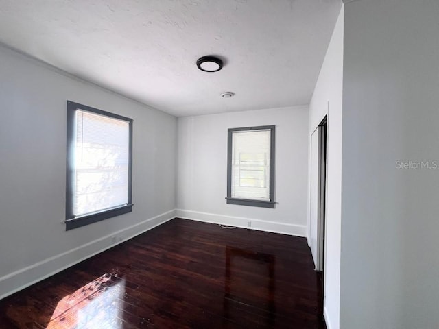 spare room with dark hardwood / wood-style floors and plenty of natural light