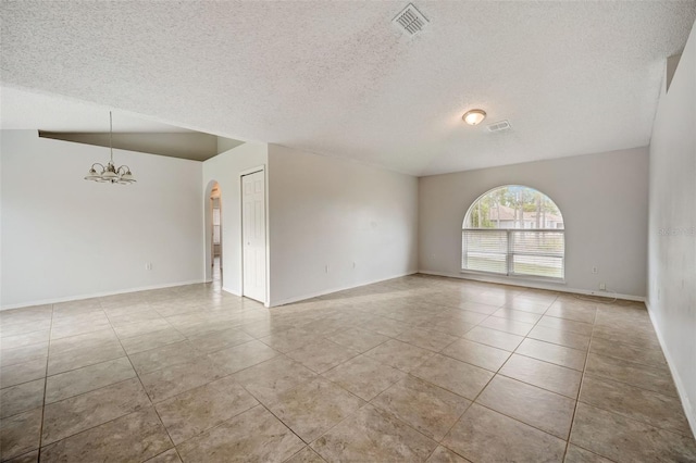 tiled empty room with a textured ceiling and a chandelier