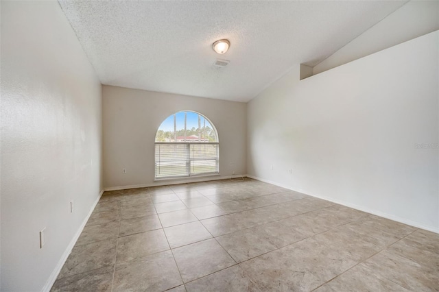 tiled empty room featuring lofted ceiling and a textured ceiling