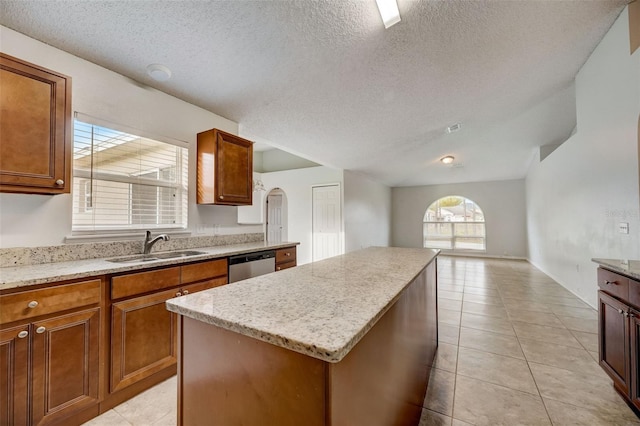 kitchen with a center island, stainless steel dishwasher, light tile floors, and light stone counters