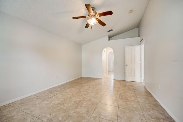 spare room with ceiling fan, vaulted ceiling, and light tile flooring