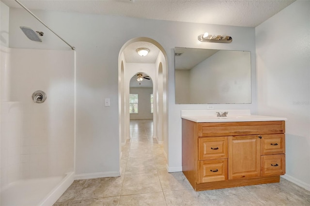 bathroom with walk in shower, a textured ceiling, vanity with extensive cabinet space, and tile flooring