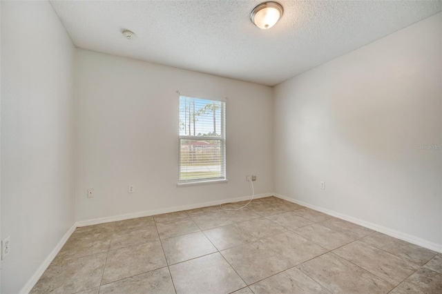 empty room with light tile flooring and a textured ceiling