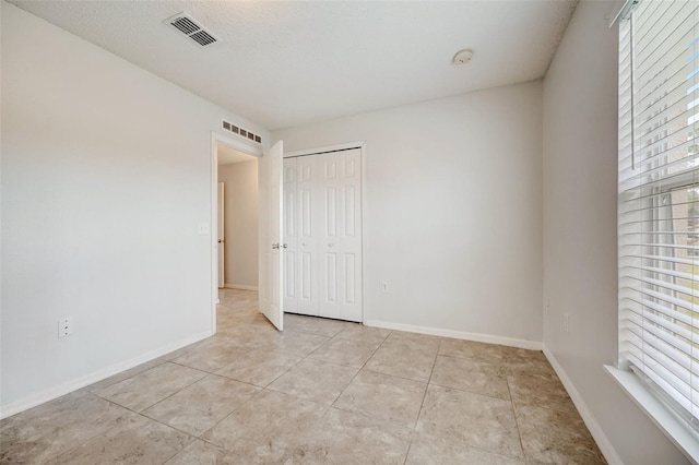 empty room featuring light tile floors and a textured ceiling