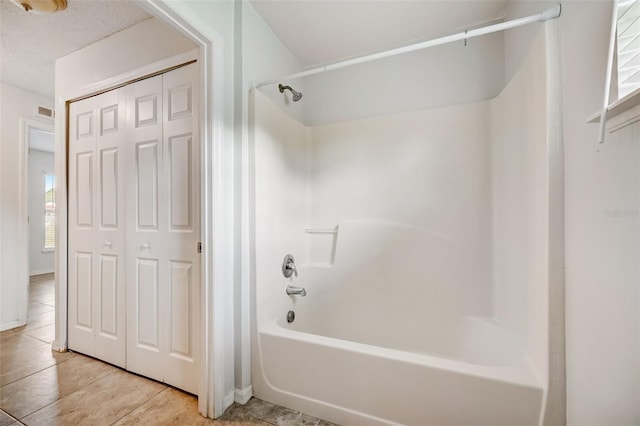 bathroom featuring a textured ceiling, tile flooring, and bathing tub / shower combination