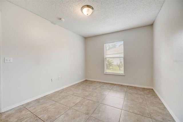 tiled empty room featuring a textured ceiling